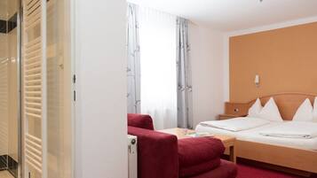 Une chambre d’hôtel avec un lit, un bureau, une chaise et une armoire.