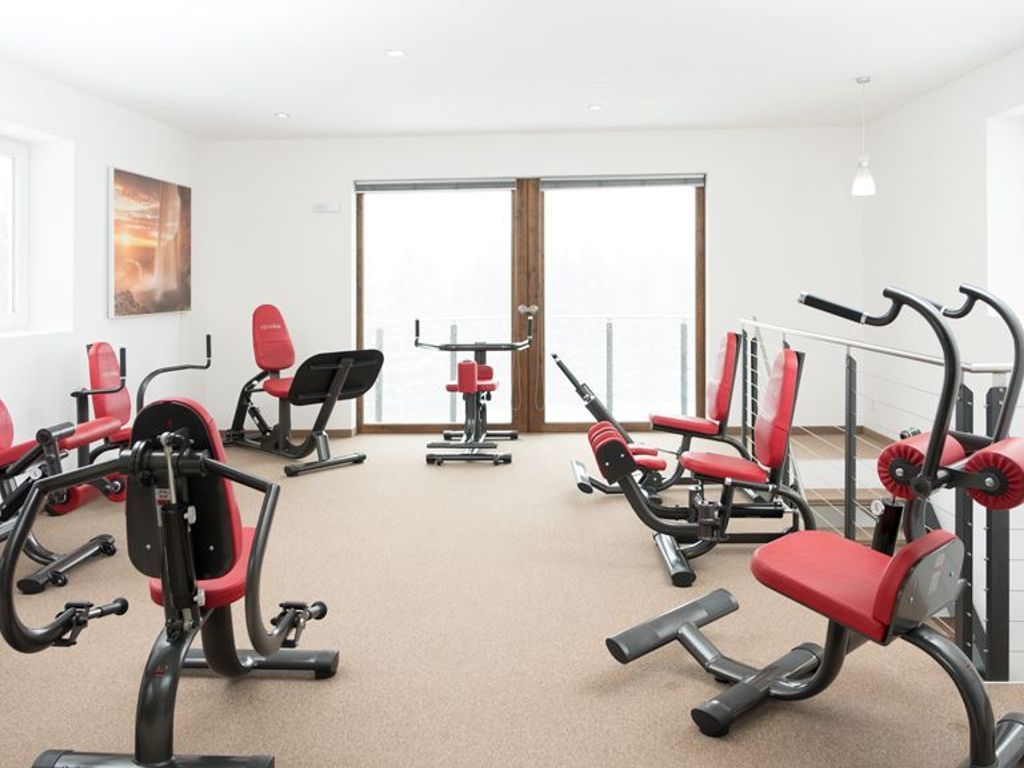 Une salle de sport équipée de divers appareils d’exercice, dotée d’une grande fenêtre et d’une porte.