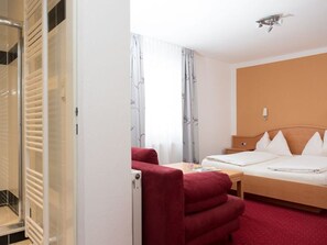 A hotel room with a bed, a desk, a chair, and a wardrobe. - Double room with extra bed - Pension Irlingerhof *** (Guggenberg)