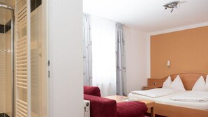 A hotel room with a bed, a desk, a chair, and a wardrobe. - Double room with extra bed - Pension Irlingerhof *** (Guggenberg)