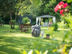 Ein Garten mit einem Pavillon, Stühlen und einer Statue.