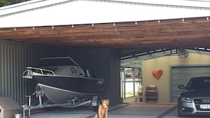 Un garage avec une remorque pour bateau, un chien et une voiture.