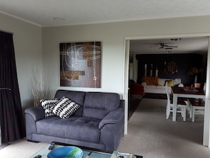 A living room with a grey sofa, a coffee table, and a dining area with a white table and chairs.