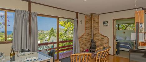 Una habitación amplia con comedor, chimenea y balcón con vistas al mar.