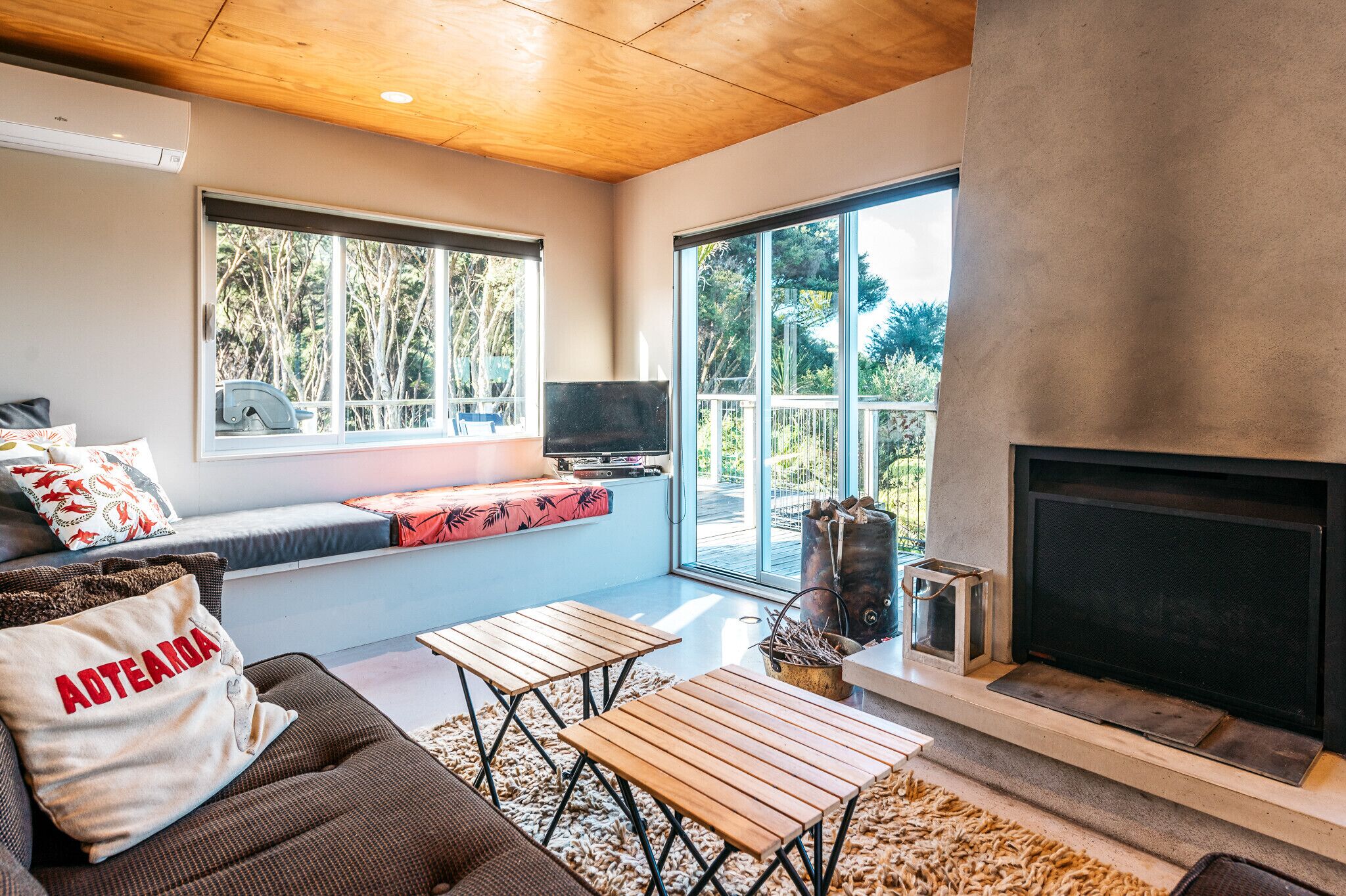 A modern living room with a fireplace, large windows, a seating area, and a television.