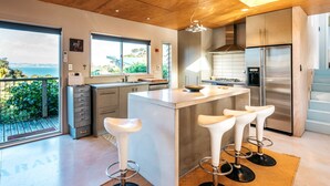 Una cocina moderna con una isla grande, taburetes de bar y vistas al exterior.