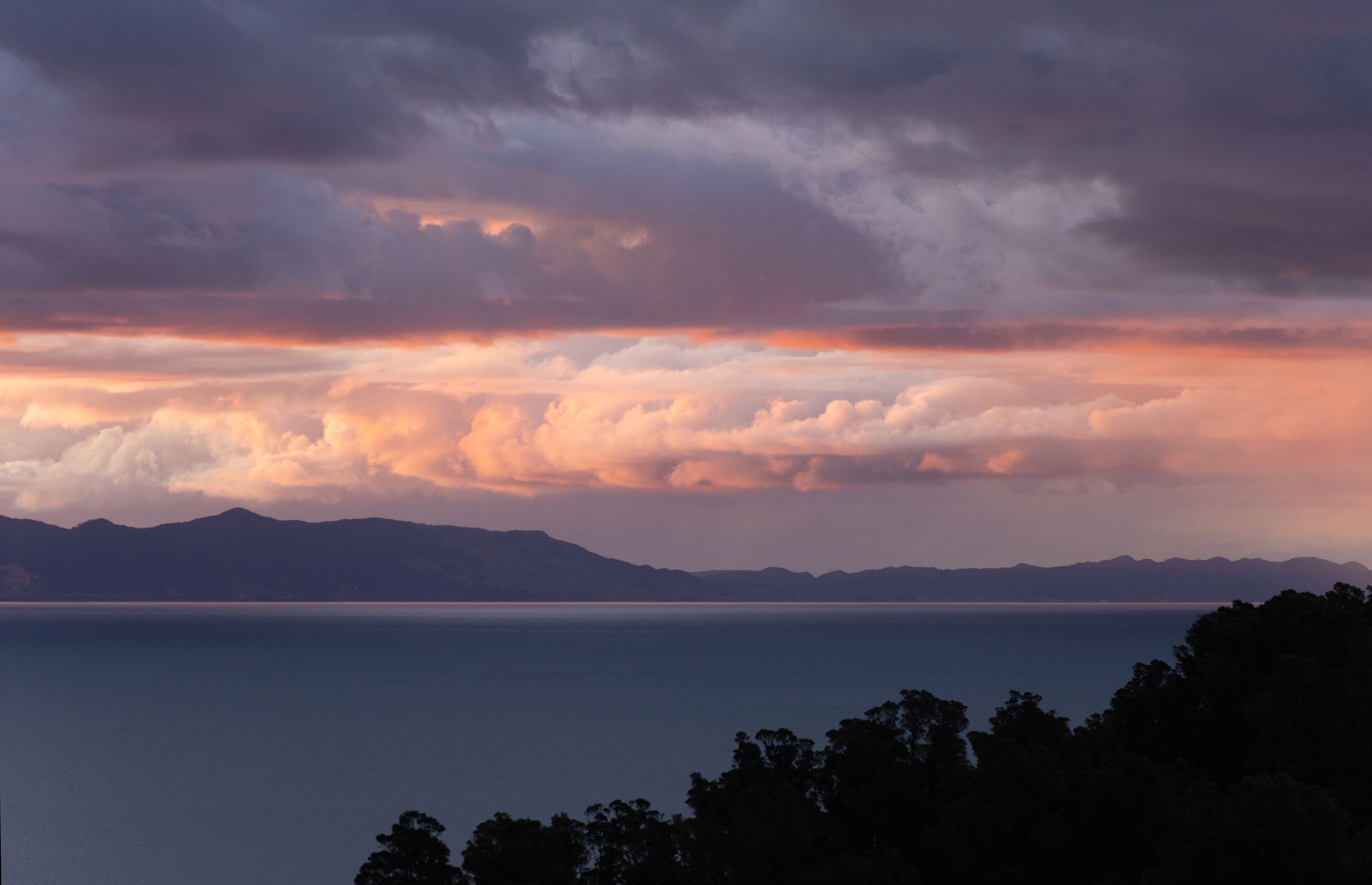 A coastal landscape with mountains in the background and a body of water in the foreground.