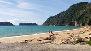 A beach with clear turquoise water, rocky outcrops, and lush green hills in the background. - Beau Vista Pohora - views to die for! (Pohara Beach)