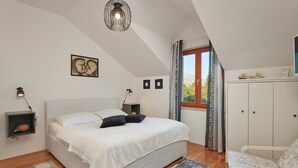 Une chambre à coucher avec un lit, des tables de chevet, une armoire et une fenêtre avec des rideaux.