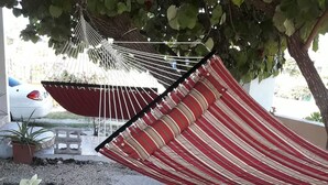 A hammock under a tree, a white car, and a gravel path. - Point Of View Townhouse (Nassau)