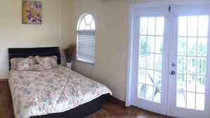 A bedroom with a bed, a window, and a door. - Point Of View Townhouse (Nassau)