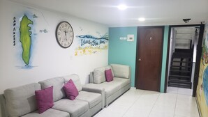 A living room with two sofas, a clock, and a wall mural. - Plaza del Mar (San Andrés)