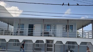 A building with a balcony, a motorcycle parked in front, and a person standing nearby. - Plaza del Mar (San Andrés)