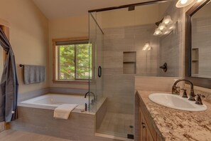 Un bagno moderno con doccia a vetro, una vasca freestanding e un vanità con lavabo.