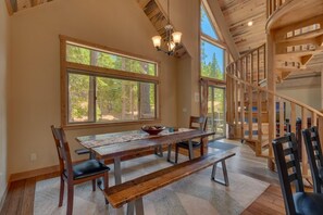 Un'ampia sala da pranzo con un tavolo e panche di legno, ampie finestre e una scala a chiocciola.
