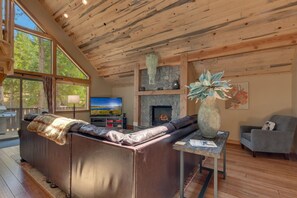 A cozy living room with a fireplace, leather sofa, and a television.