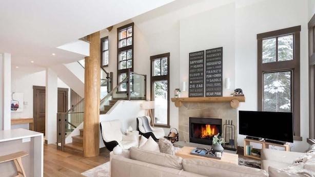 Ein geräumiges Wohnzimmer mit Kamin, Fernseher und einer Treppe, die in eine andere Ebene führt.
