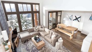 Ein modernes Wohnzimmer mit großem Fenster, einer Couch, einem Couchtisch und einem Essbereich.