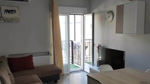 A modern living room with a sofa, a dining table, and a TV. - Barajas Apartment. Airport/IFEMA (Madrid)