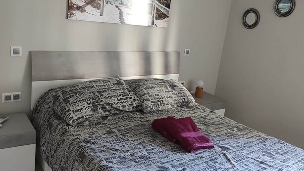 A bedroom with a bed, a headboard, a nightstand, a wall-mounted picture, and a window. - Barajas Apartment. Airport/IFEMA (Madrid)
