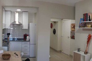 Una cocina moderna con armarios blancos, una campana extractora de acero inoxidable y un comedor con una mesa y sillas.