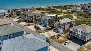 A coastal residential area with houses, a swimming pool, and a view of the ocean. - Pelican's Perch | 320 ft from the beach | Private Pool, Hot Tub | Corolla (Corolla)