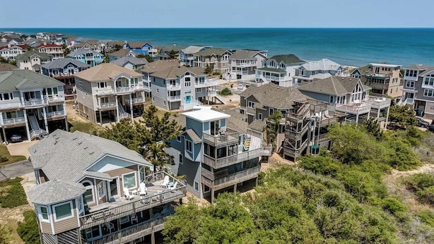 A coastal residential area with multiple two-story houses featuring balconies and waterfront views. - Pelican's Perch | 320 ft from the beach | Private Pool, Hot Tub | Corolla (Corolla)