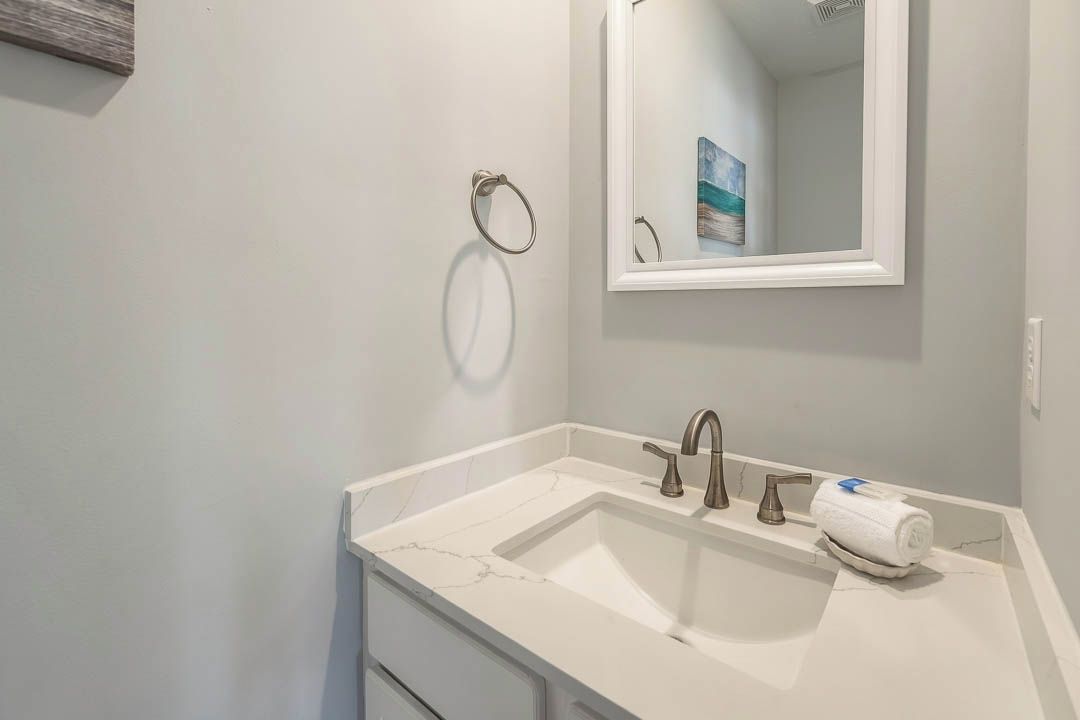 A bathroom with a white sink, a mirror, and a towel ring.