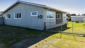 A single-story mobile home with a number '10' on the side, a small porch, and a fenced yard.