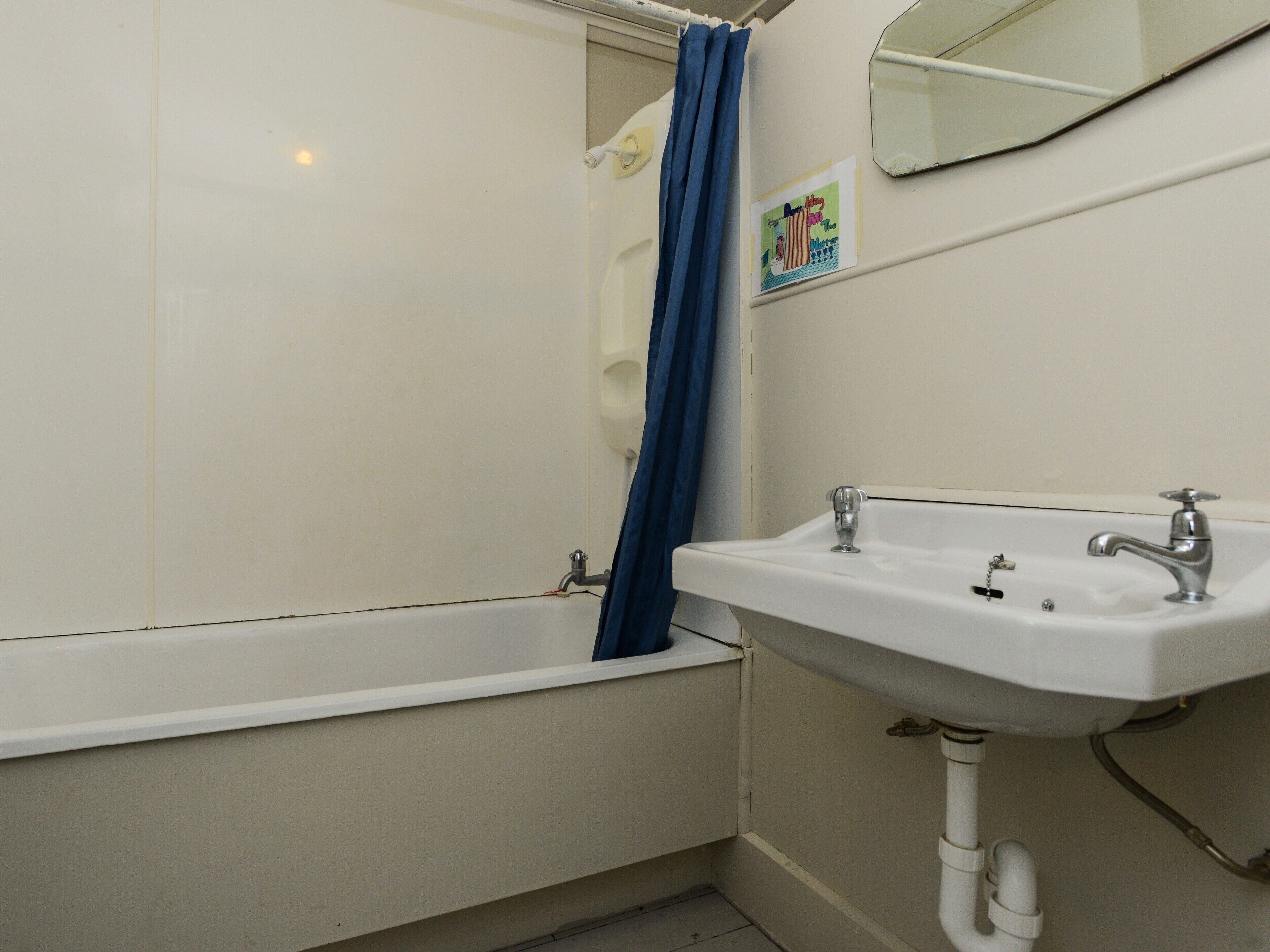 A bathroom with a bathtub, a sink, and a mirror.