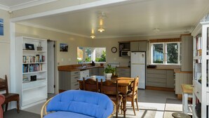 A spacious kitchen with a dining area, a bookshelf, and a blue chair.