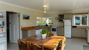 A modern kitchen with a wooden dining table, chairs, a built-in oven, microwave, and a sink.