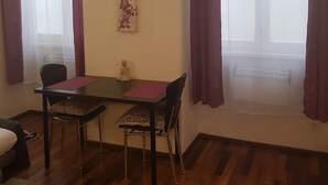 Un comedor con una mesa y sillas, un adorno en la pared y ventanas grandes con cortinas.