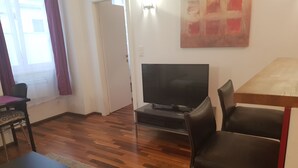 Una sala de estar con televisor, una mesa de comedor y dos sillas.