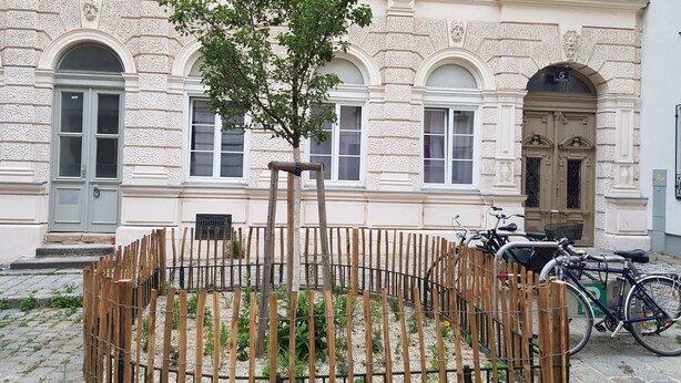 Un edificio de fachada clásica, una cerca de madera y una bicicleta estacionada afuera.
