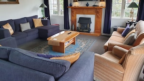 A living room with a fireplace, sofas, a television, and a large window. - Charmae Guest House by the river.
7 x Beds, (sleeps 10)
Plus powered van site (Wanganui Township)
