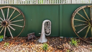 A brass tuba placed between two large, rusted wheels against a green wall. - Charmae Guest House by the river.
7 x Beds, (sleeps 10)
Plus powered van site (Wanganui Township)