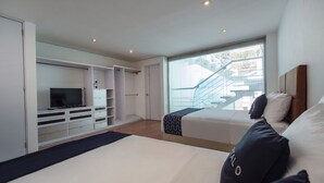 Un dormitorio con cama, televisor, armario y ventana con vista a una escalera.