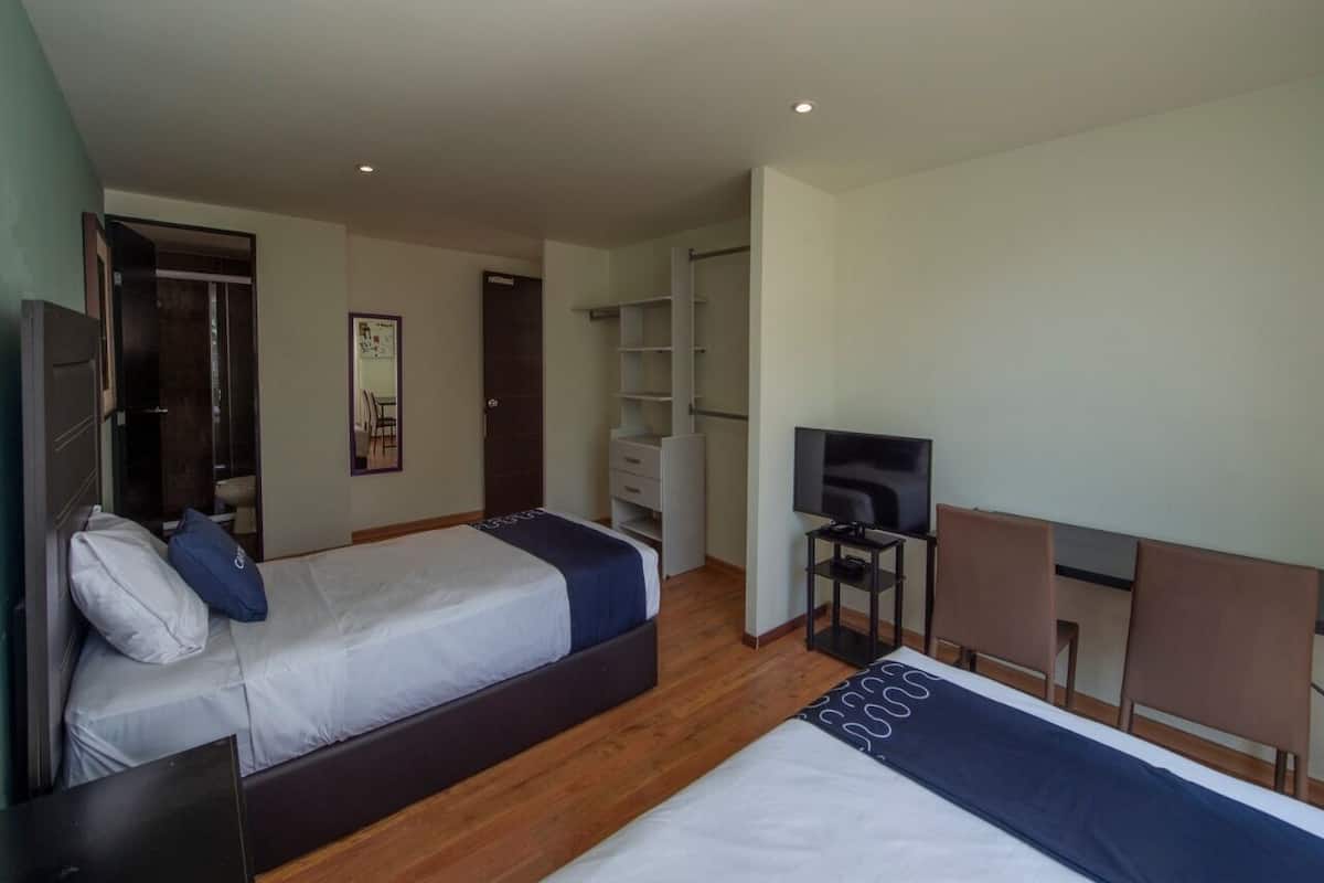 A hotel room with two beds, a TV, a desk, and a wardrobe.