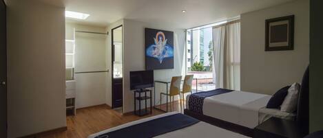 Habitación de hotel con dos camas, televisión, escritorio y vistas al exterior.