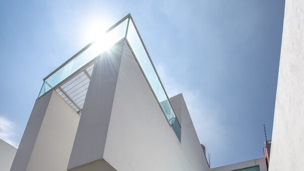 Una estructura arquitectónica moderna con un balcón de vidrio, una escalera y vistas al cielo.