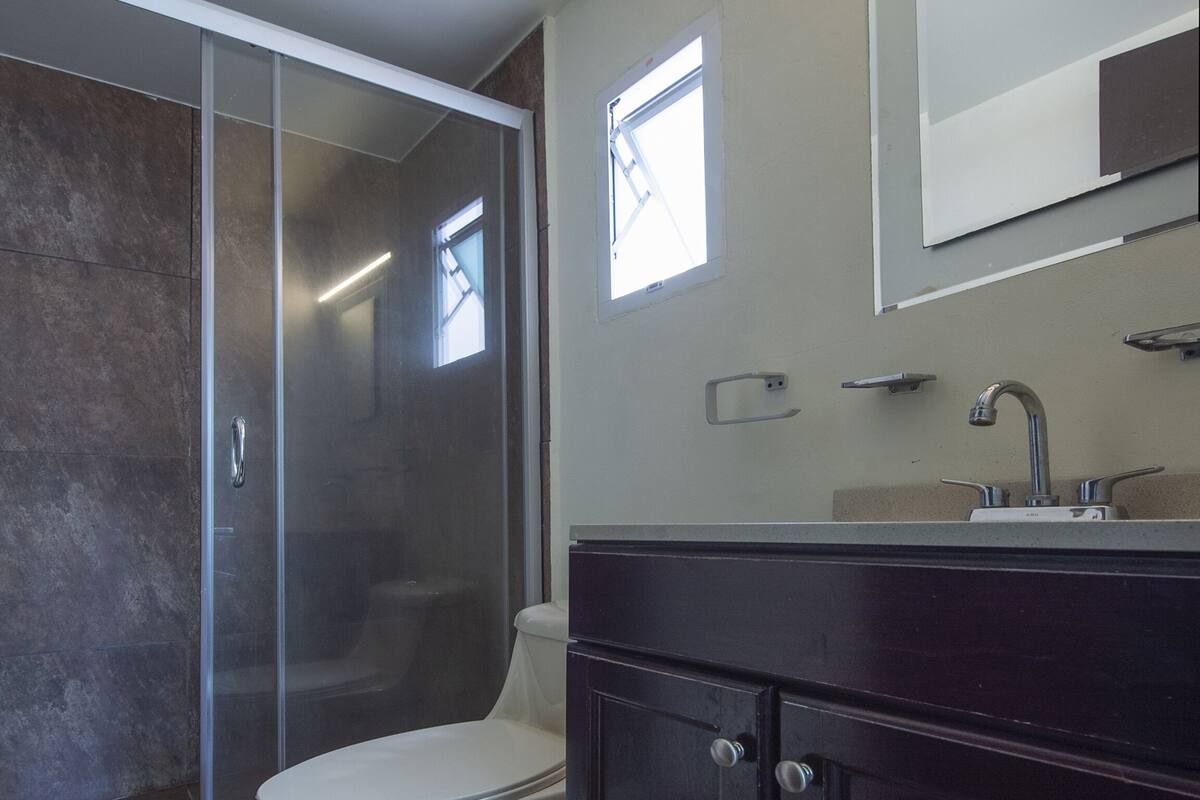 A modern bathroom with a toilet, shower, and vanity.