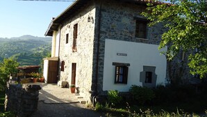 A stone house with a white facade, a visible door, and a small porch area.