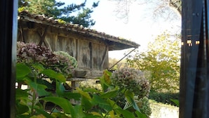 A rustic wooden building with a sloped roof, surrounded by lush greenery and flowering plants.