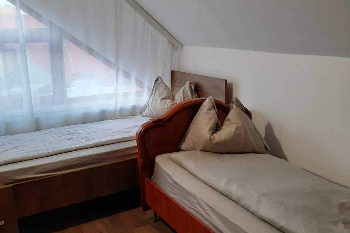 Ein kleines Zimmer mit einem Einzelbett, geneigter Decke und Holzboden.