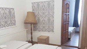 Un dormitorio con dos camas, una mesita de noche, una lámpara y una puerta que da a otra habitación.