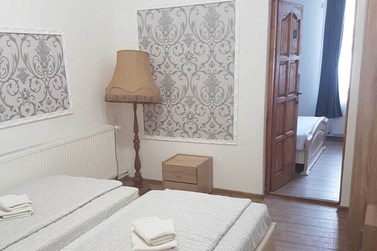 Ein Schlafzimmer mit zwei Betten, einem Nachttisch, einer Lampe und einer Tür zu einem anderen Raum.