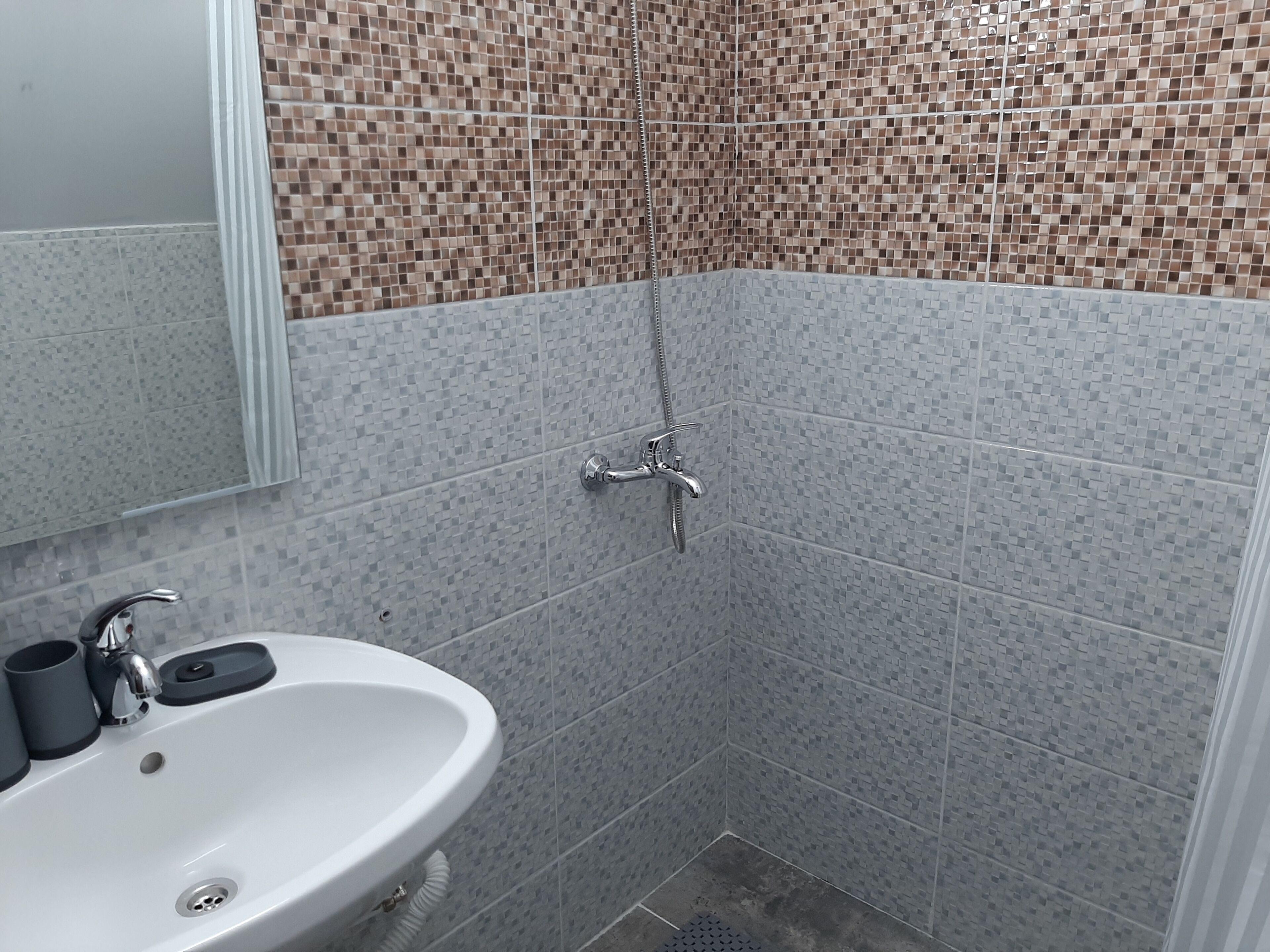 A bathroom with a sink, mirror, and shower area.