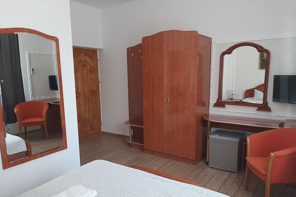 Ein Hotelzimmer mit Bett, Schreibtisch, Kleiderschrank, Spiegel und Stuhl.
