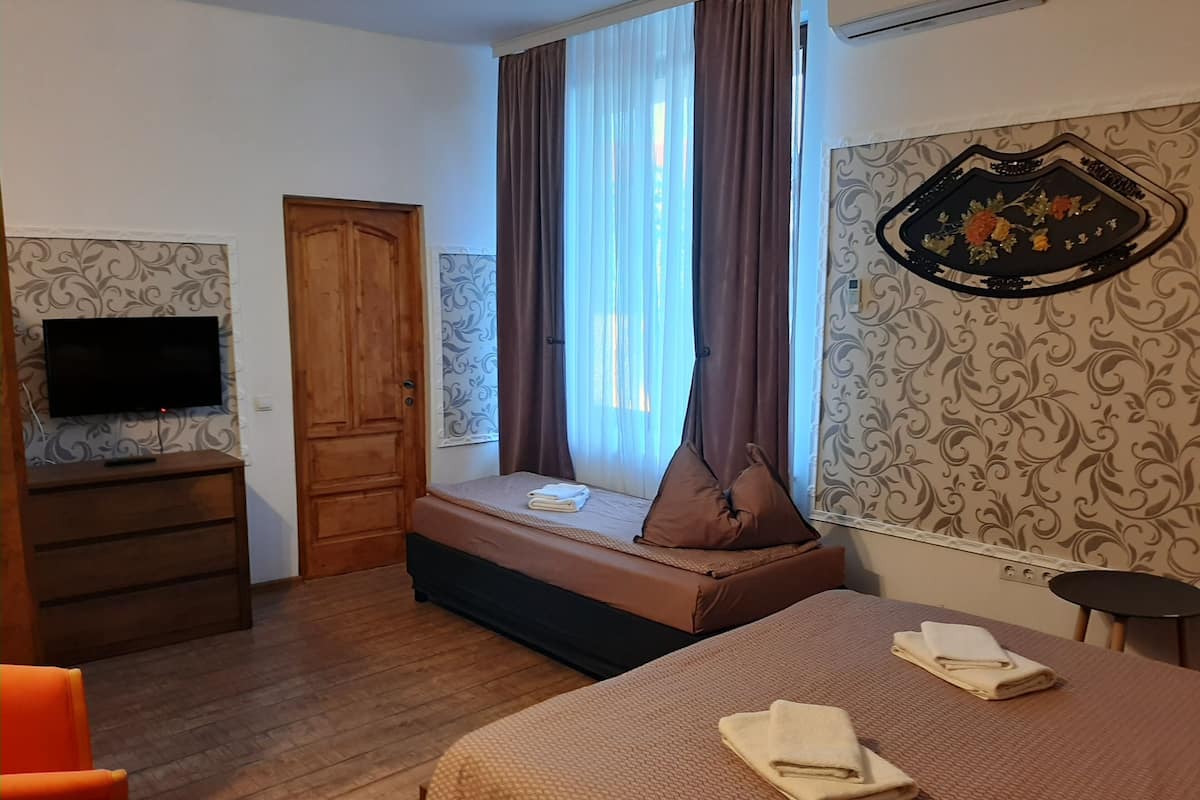 Ein Zimmer mit einem Bett, einem Schreibtisch, einem Fernseher und einem Fenster mit Vorhängen.